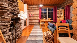 A cozy log cabin interior with a stone wall, wooden dining table, and rustic furniture.