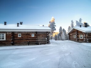 Una cabaña de troncos con techo nevado y cielo despejado.