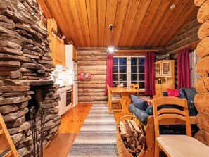 Interior acogedor de una cabaña de troncos con pared de piedra, mobiliario de madera y comedor.