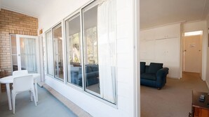 Ein modernes Wohnzimmer mit einem großen Schiebeglasfenster, einem weißen Tisch und einem blauen Sofa.