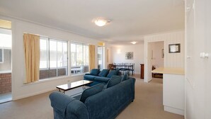 Ein modernes Wohnzimmer mit einer Sofagarnitur, einem Esstisch und einer Küchenzeile.