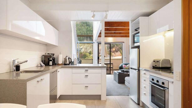 A modern kitchen with white cabinetry, stainless steel appliances, and a large island.