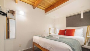 A bedroom with a wooden bed frame, white bedding, and a green throw blanket.