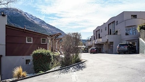 A residential street with modern houses, a mountain in the background, and parked cars.