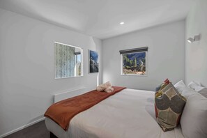 A bedroom with a bed, a window with a view, and two wall-mounted pictures. - Just the Spot,  a 500m stroll to Queenstown CBD (Queenstown)