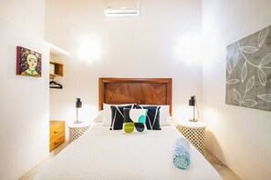 Een hotelkamer met een groot bed, bedlampen, een houten hoofdeinde, een schilderij aan de muur en een handdoek op het bed.