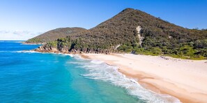 A beach with clear turquoise waters and a mountain in the background.