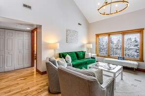 Relax in this stylish living room with a sofa, bench, and armchair, perfect for unwinding with a view of snow-covered trees.