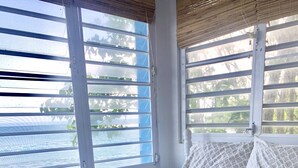 A bed with a purple quilt, a rolled towel, and two patterned pillows. - BEACH HOUSE W/ POOL (vieques)