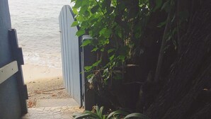 A stone pathway leading to a beach, with a gate and plants along the path. - BEACH HOUSE W/ POOL (vieques)
