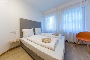 Relax in a serene space with a large bed, bedside table, and sheer curtains.
