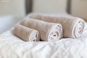 Towels neatly arranged on a bed with a textured bedspread featuring a subtle pattern.