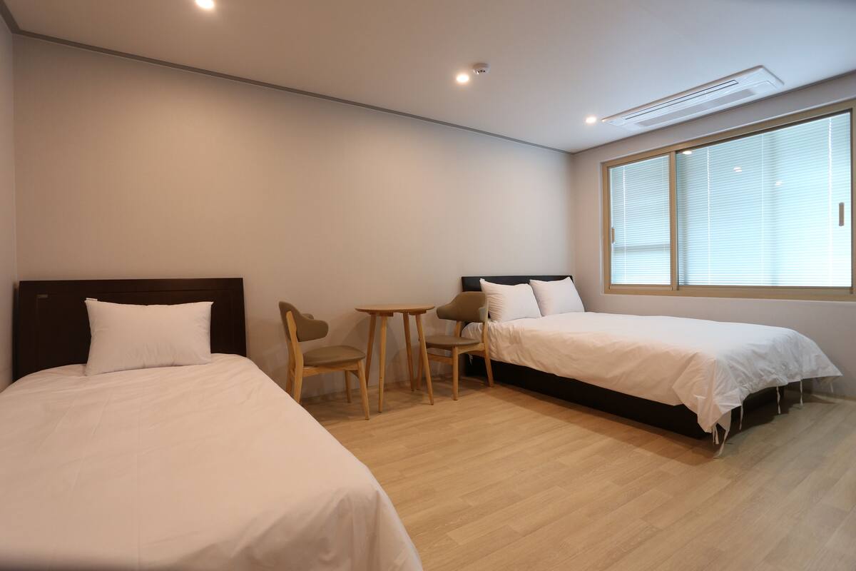 A hotel room with two beds, a small table, and chairs.