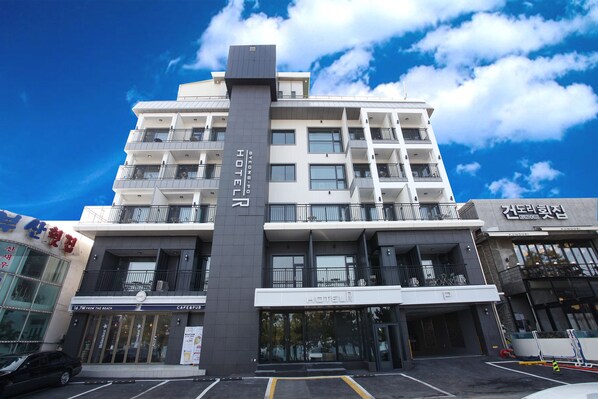 A multi-story hotel with a prominent vertical sign, balconies, and a cafe/pub at the ground level.
