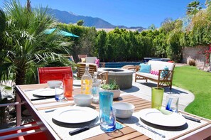Enjoy a meal al fresco in this serene outdoor dining area surrounded by lush greenery and a sparkling pool.