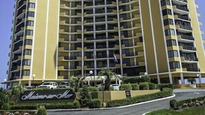 A high-rise hotel with multiple balconies, a prominent entrance with a sign, and a clear sky. - Premium-Steps 2 Beach-Wide Oceanview-Lrg Balconies-Pool-Gated-On Site Restaurant (Myrtle Beach)