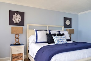 A neatly arranged bedroom with a bed, bedside tables, and wall art.