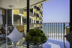 A balcony with a glass table, a metal chair, and a metal railing.