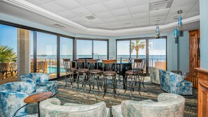 A spacious lounge area with a view of the ocean, featuring leather chairs, a wooden table, and a patterned carpet. - Premium-Steps 2 Beach-Wide Oceanview-Lrg Balconies-Pool-Gated-On Site Restaurant (Myrtle Beach)