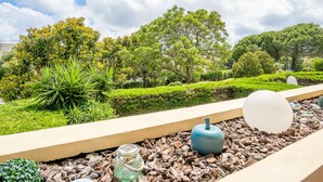 Un jardín ajardinado con diversas plantas y árboles, un sendero y objetos esféricos decorativos.