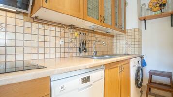 Een koelkast, een oven, een vaatwasser, kookgerei, borden en bestek