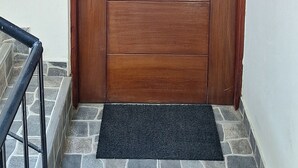 Une porte en bois portant le numéro 302, une poignée en métal et un paillasson noir devant l’entrée.