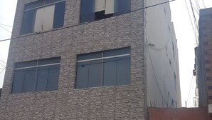 Un immeuble à plusieurs étages doté d’une façade à motifs, de grandes fenêtres et d’une porte bien visible avec une enseigne.
