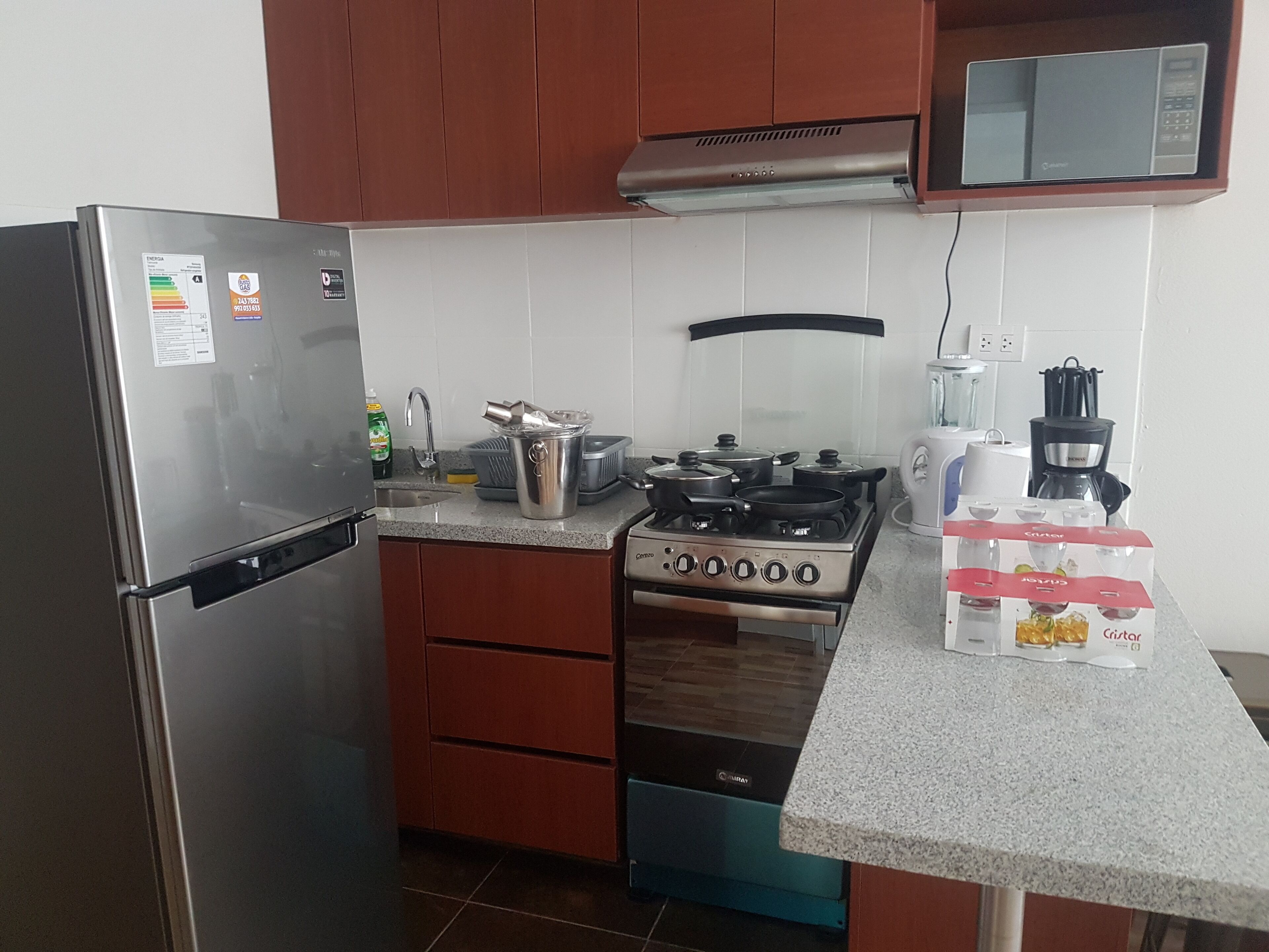 A kitchen with a stainless steel refrigerator, a gas stove, a microwave, and a coffee maker.