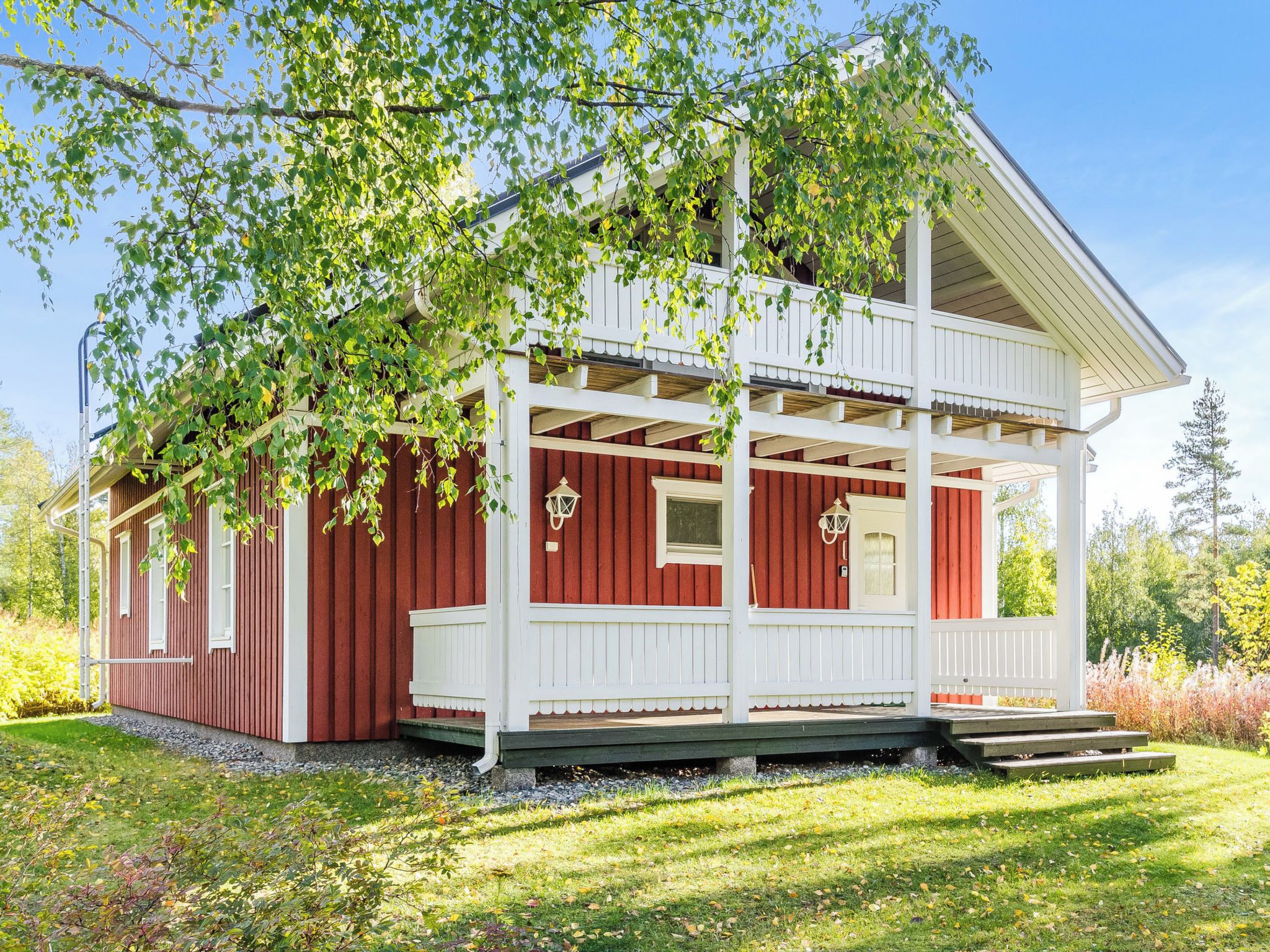A red and white wooden building with a porch and a small window.