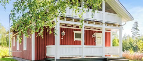 A red and white wooden building with a porch and a small window.