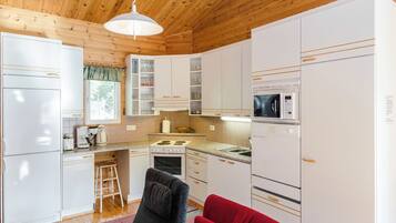 A modern kitchen with white cabinets, a microwave, a stove, and a sink.