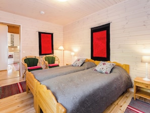 Ein Zimmer mit zwei Holzbetten, einer Küchenzeile und Holzboden.
