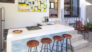 A modern kitchen with a central island, bar stools, and a large abstract painting.