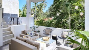 A modern outdoor living area with a sofa set, a dining table, and chairs. There is a staircase leading to an upper level.