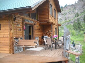A wooden cabin with a porch, outdoor seating, and a view of the surrounding landscape. - Trout Tales Lodge, Dearborn River front, blue ribbon fishing. Cascade, Craig MT. (Cascade)