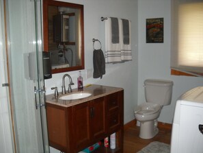 A bathroom with a sink, mirror, towel rack, toilet, and a poster on the wall. - Trout Tales Lodge, Dearborn River front, blue ribbon fishing. Cascade, Craig MT. (Cascade)