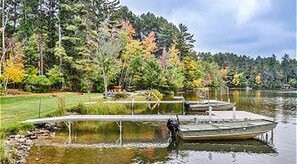 A calm lake with docked boats, surrounded by trees with autumn foliage.