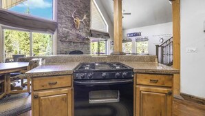 Una cocina con una isla central, armarios de madera, una estufa negra y una pared de piedra.