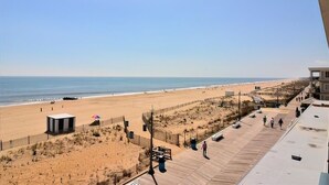 A beach view with a wooden boardwalk, a lifeguard tower, and a sandy beach. - OCEAN FRONT CONDO.  ENJOY YOUR MORNING COFFEE SITTING ON YOUR PRIVATE BALCONY WATCHING THE SUNRISE. (Rehoboth Beach)