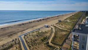 A beach view with a boardwalk, sandy beach, and ocean.