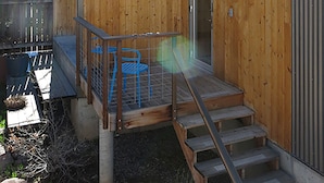 Una baita di legno con un portico, una ringhiera in metallo e una scala che conduce a una porta.
