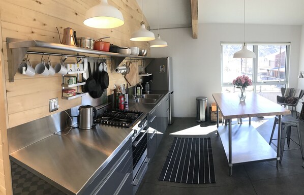 A modern kitchen with stainless steel appliances, hanging pots, and a large window providing natural light. - Modern design retreat in Downtown Durango (Durango)