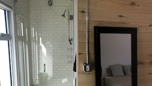 Un bagno moderno con cabina doccia in vetro, scaldabagno a vista e parete in legno.