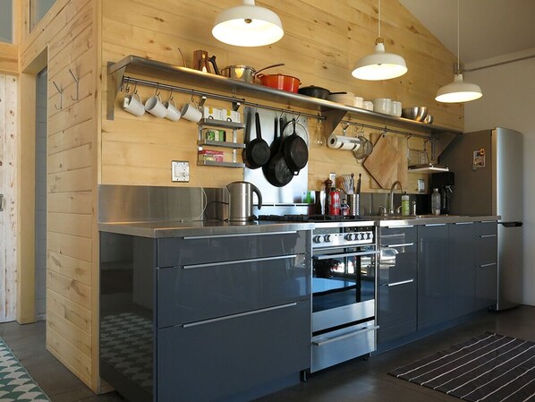 Une cuisine moderne dotée d’appareils électroménagers en acier inoxydable, de meubles de rangement en bois et de luminaires suspendus.