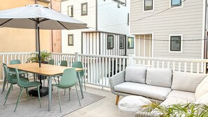 A balcony with a table and chairs, a sofa, and potted plants. - 65 Steps to Ocean • Private Home • 2-Car Garage (San Diego)