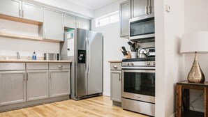 A modern kitchen with grey cabinets, stainless steel appliances, and a wooden floor. - 65 Steps to Ocean • Private Home • 2-Car Garage (San Diego)
