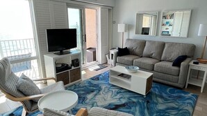 Una sala de estar moderna con televisor, sofá y sillón.