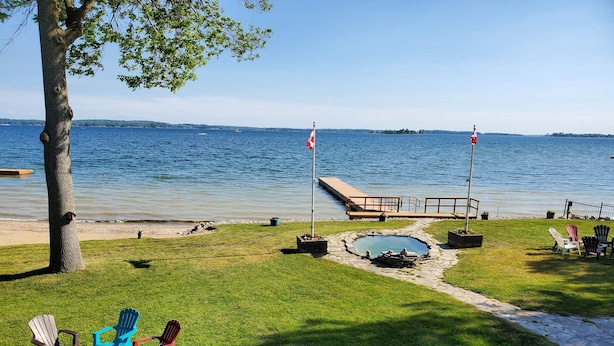 A lakeside patio with Adirondack chairs, a fire pit, and a small pool. - Home of 1000 Island#1-Directly on STL  river, private beach & FREE boat docking  (Gananoque)