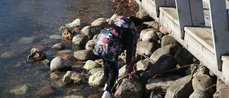 A person standing on rocks near a wooden bridge over a clear stream.