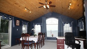 A dining area with a table, chairs, and a view of the water. - Home of 1000 Island#1-Directly on STL  river, private beach & FREE boat docking  (Gananoque)